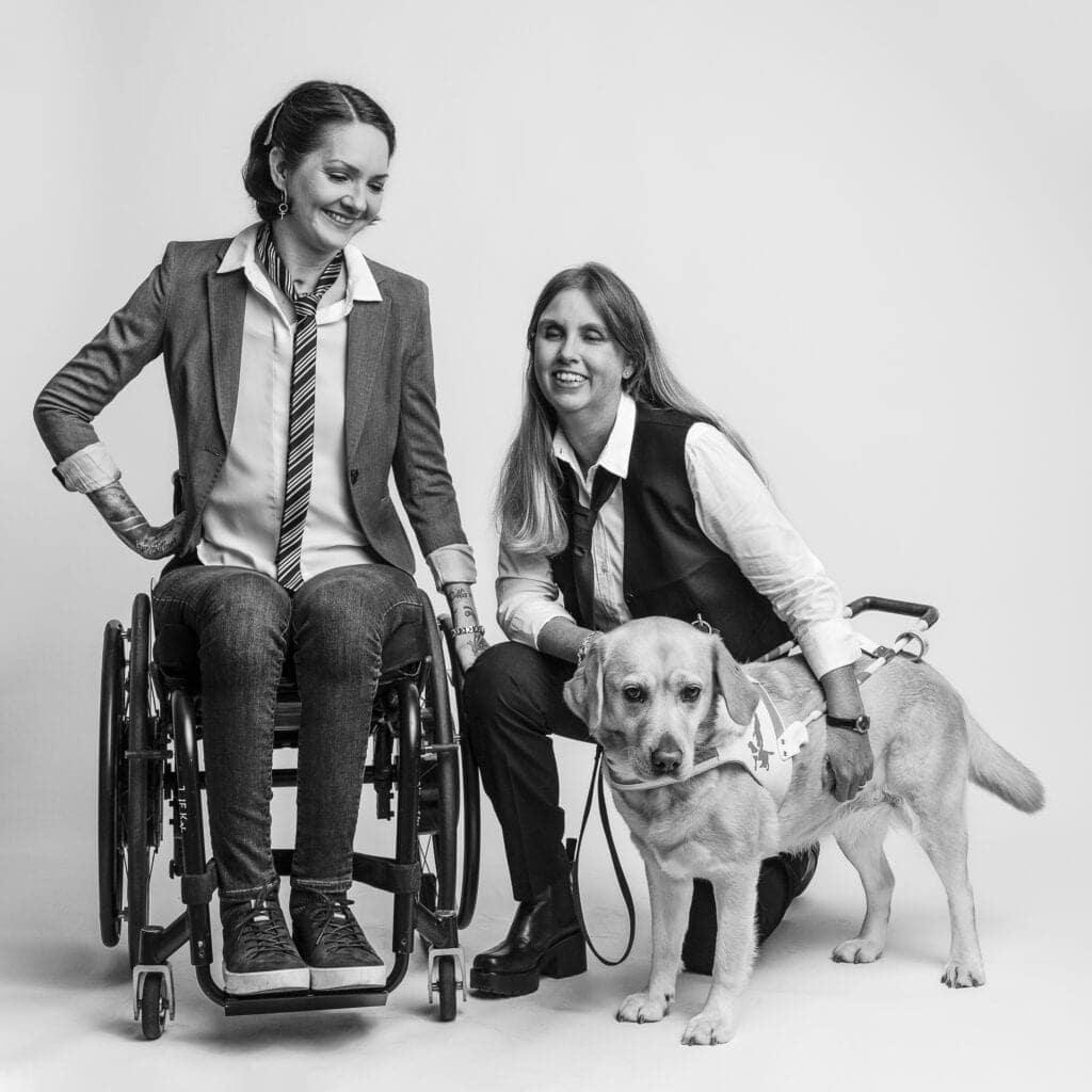 Yasmin Nilson och Anna Bergholtz i fotostudio. Anna står på knä intill sin ledarhund.