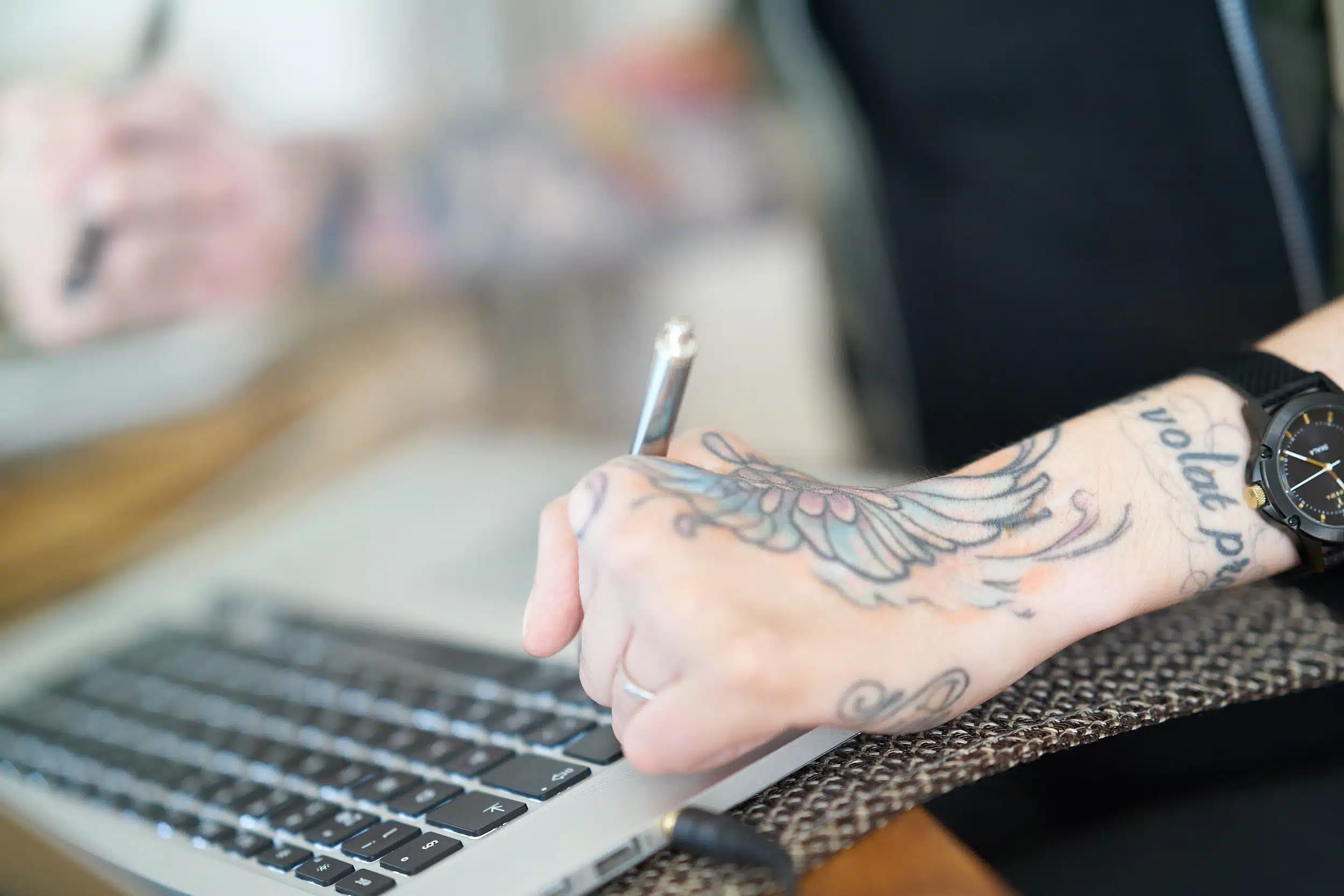 Händer med tatuering skriver på datortangentbord