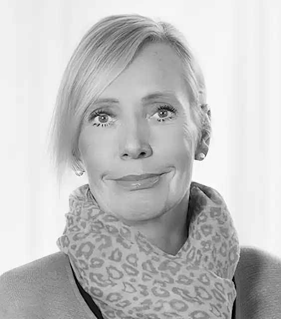 Porträttbild Åsa Maria Wallin. Hon har långt ljust hår, en prickig scarf och en ljus tröja