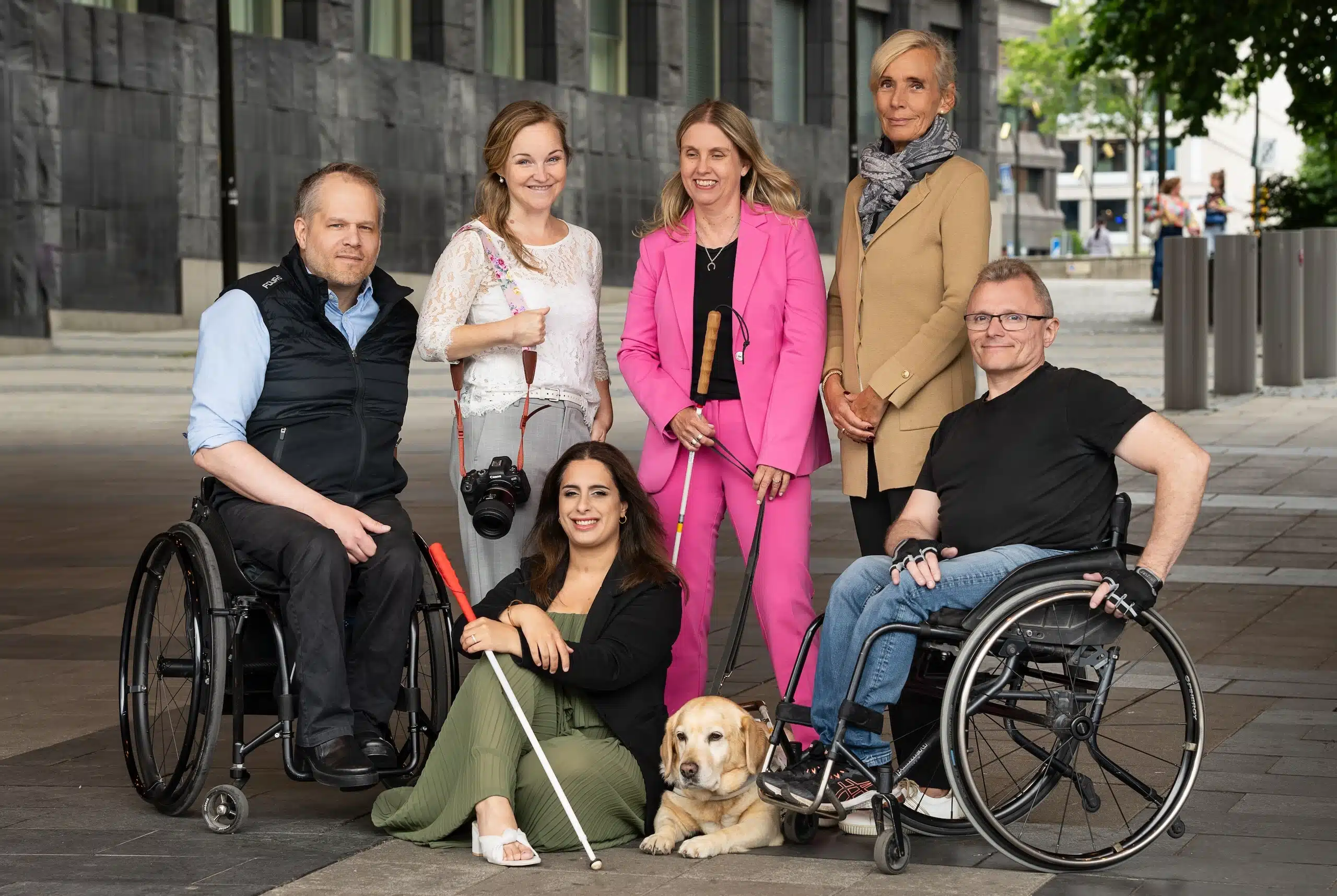 Gruppbild utomhus i stadsmiljö på Staffan, Helena, Anna, Åsa, Parimah och Lars-Göran samt Annas ledarhund som ligger på marken framför gruppen.