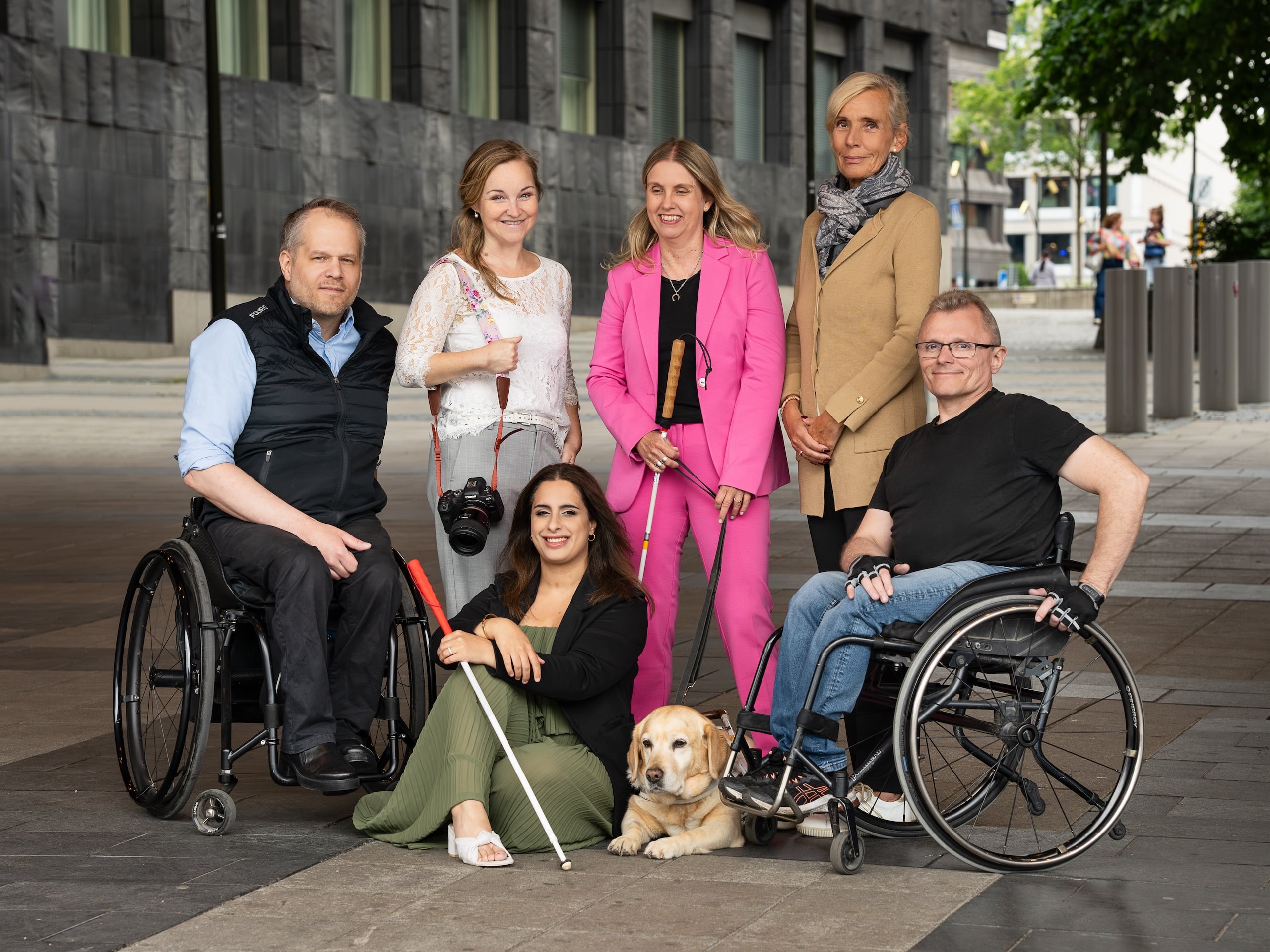 Gruppbild utomhus i stadsmiljö på Staffan, Helena, Anna, Åsa, Parimah och Lars-Göran samt Annas ledarhund som ligger på marken framför gruppen.