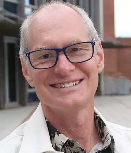 Porträttfoto Emil Erdtman. Han har kort grått hår, glasögon och vit jacka.