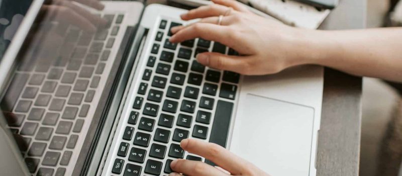 Händer jobbar på en laptop på ett skribord